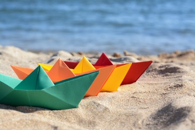 Photo of Many paper boats near sea on sunny day. Space for text