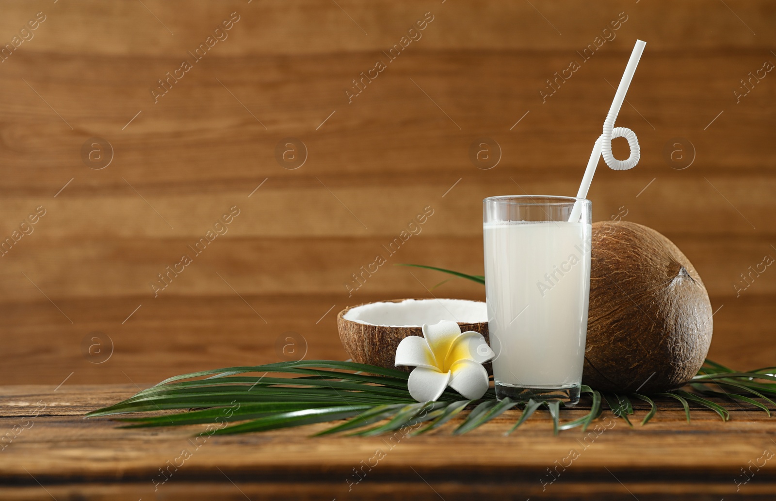 Photo of Composition with glass of coconut water on wooden background. Space for text