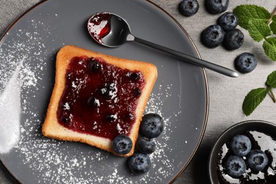 Photo of Delicious toast served with jam and blueberries on grey wooden table, flat lay