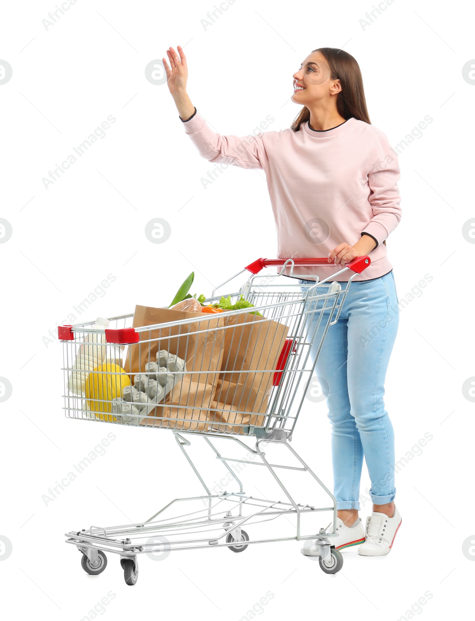 Photo of Young woman with full shopping cart on white background