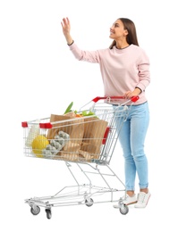 Young woman with full shopping cart on white background