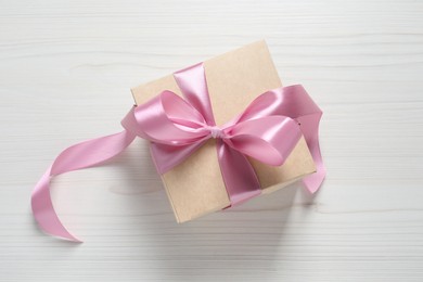 Photo of Beautiful gift box with pink bow on white wooden background, top view