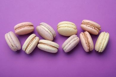 Delicious colorful macarons on purple background, flat lay