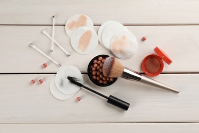 Photo of Dirty cotton pads, swabs and cosmetic products on white wooden background, flat lay
