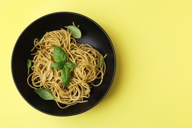 Photo of Delicious pasta with pesto sauce and basil on yellow background, top view. Space for text