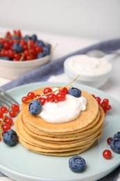 Photo of Tasty pancakes with natural yogurt, blueberries and red currants on table. Space for text