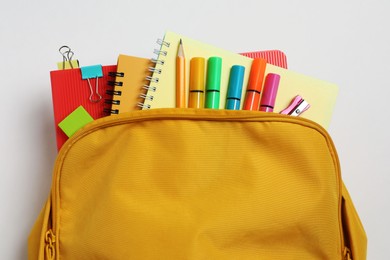 Photo of Backpack with different school stationery on white background, top view