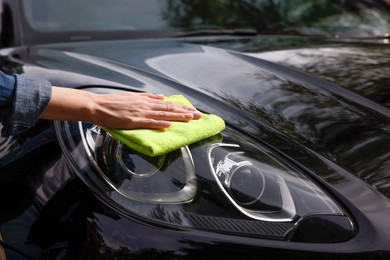 Photo of Woman wiping her modern car with rag, closeup