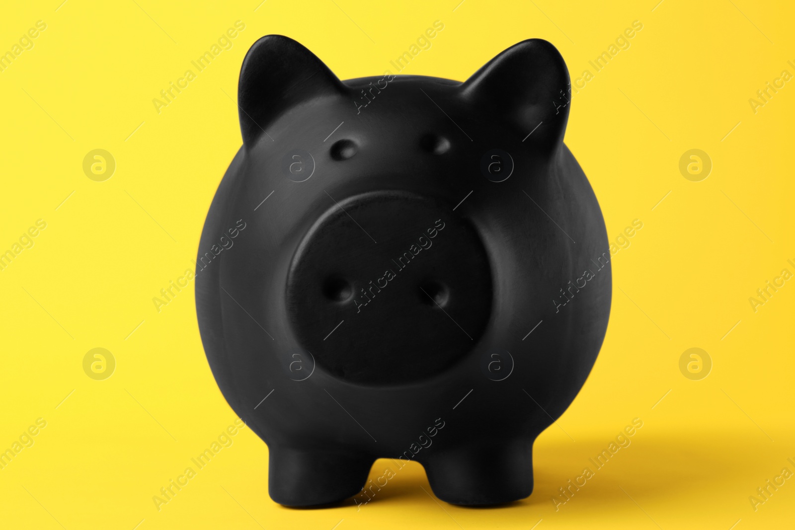 Photo of Ceramic piggy bank on yellow background, closeup. Financial savings