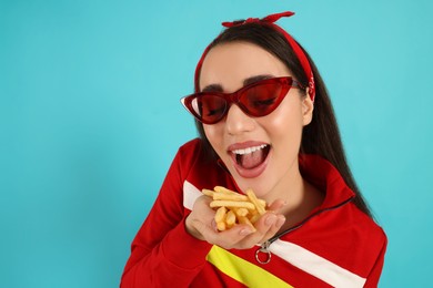 Photo of Beautiful young woman eating French fries on light blue background