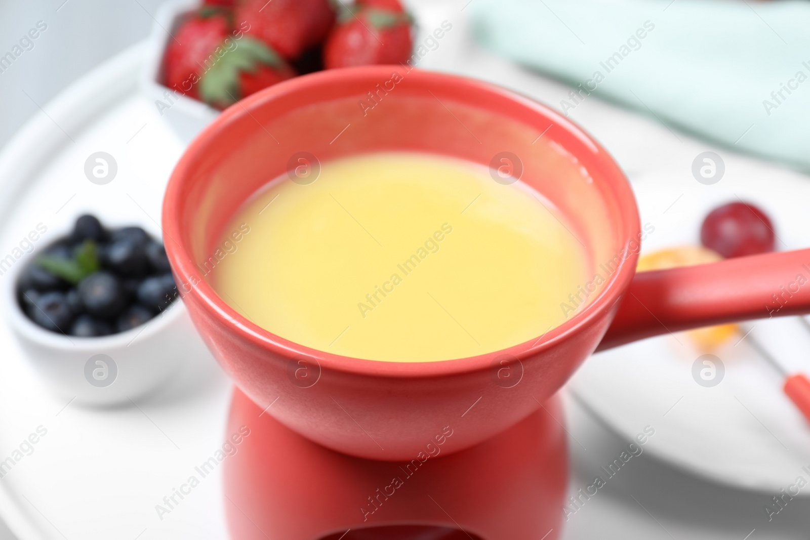 Photo of Ceramic pot with white chocolate fondue on table, closeup