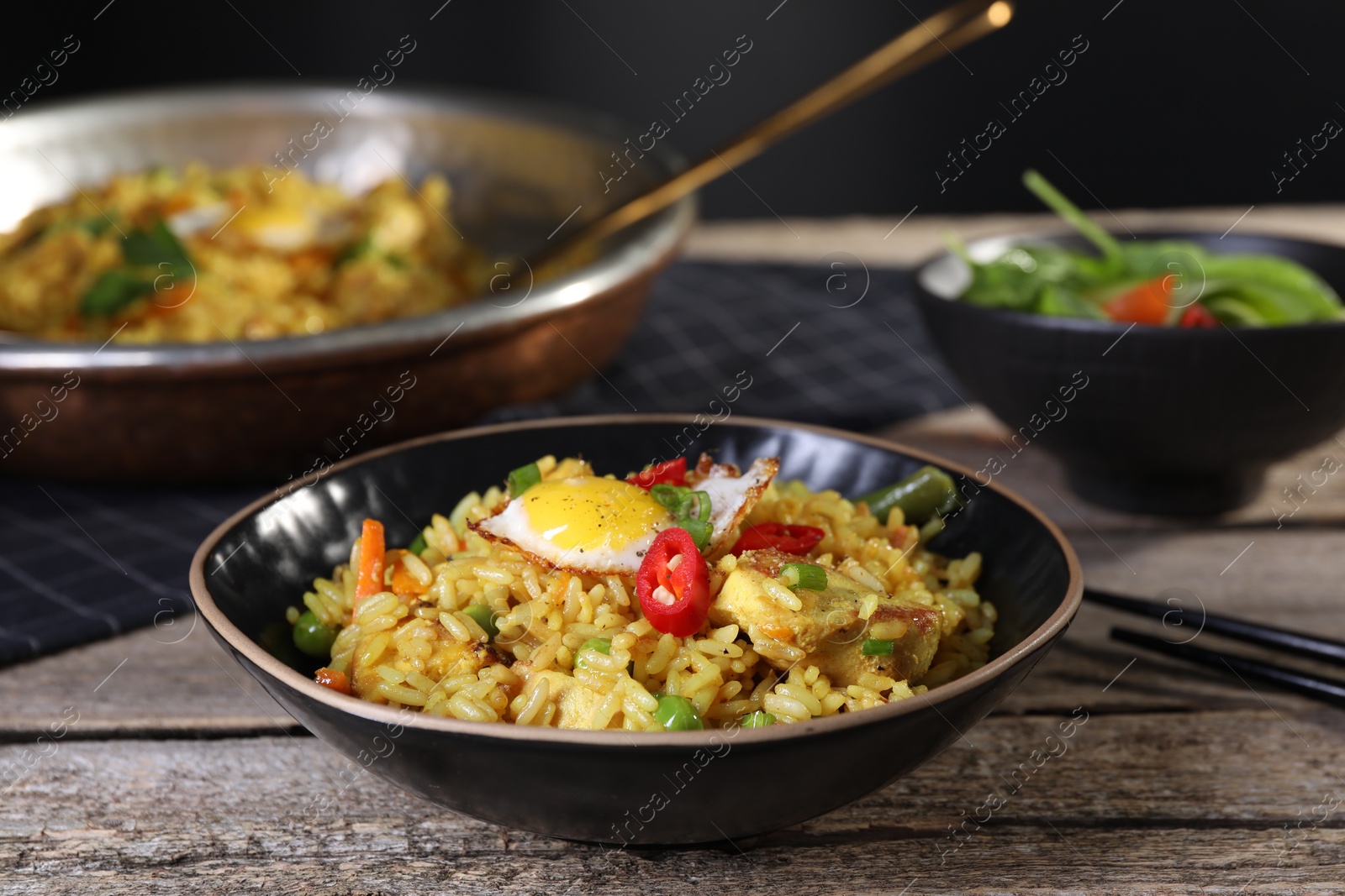 Photo of Tasty rice with meat, egg and vegetables in bowl on wooden table