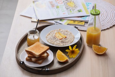 Photo of Wooden tray with delicious breakfast and beautiful flower on table