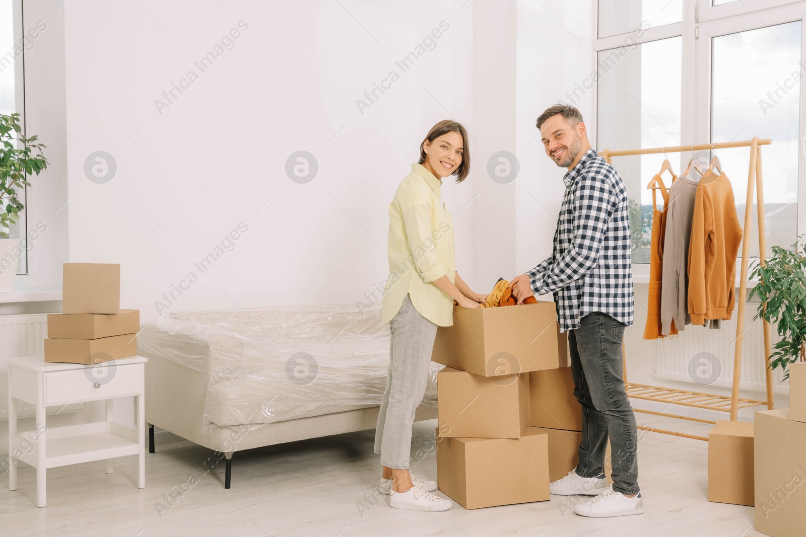 Photo of Happy couple unpacking box in new apartment. Moving day