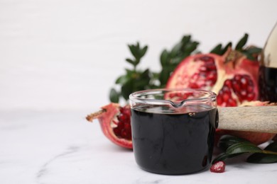 Photo of Tasty pomegranate sauce on white marble table, closeup. Space for text