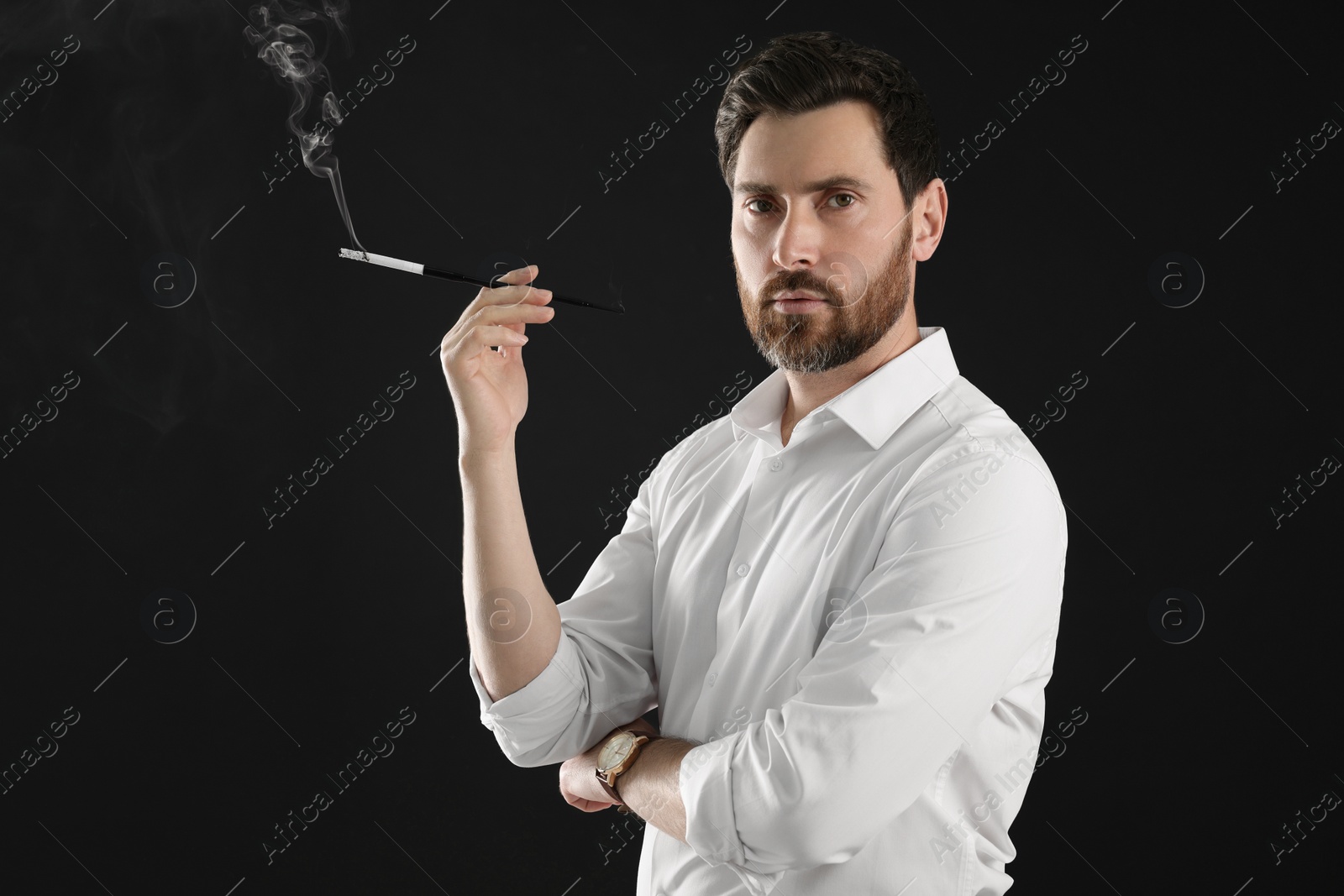 Photo of Man using long cigarette holder for smoking on black background, space for text