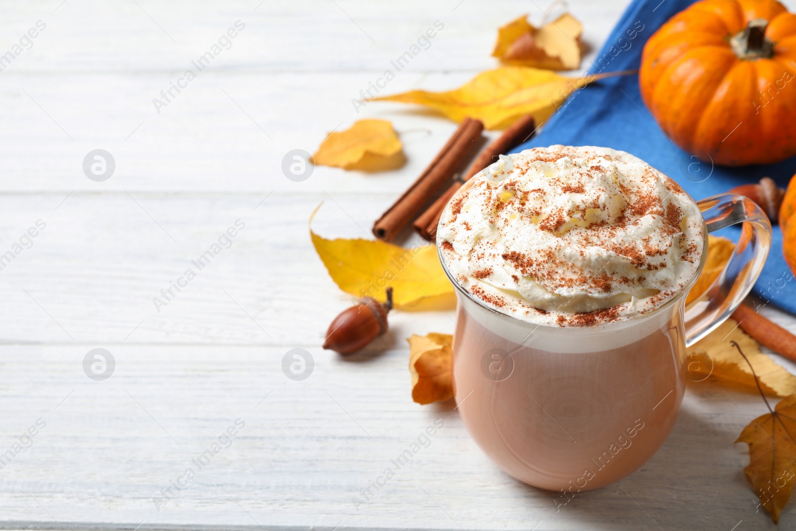 Photo of Delicious pumpkin latte on white wooden table, closeup. Space for text