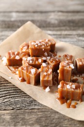 Photo of Yummy candies with caramel sauce and sea salt on wooden table