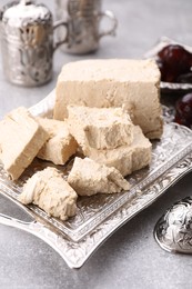 Pieces of tasty halva served on light grey table, closeup