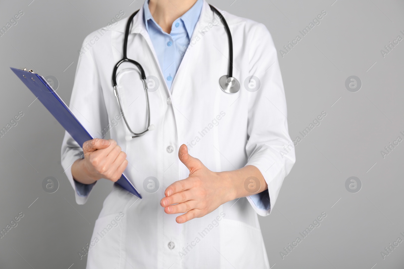 Photo of Doctor offering handshake on light grey background, closeup