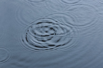 Photo of Rain drops falling down into puddle outdoors