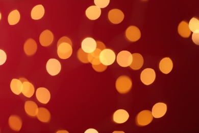 Blurred view of festive lights on red background. Bokeh effect