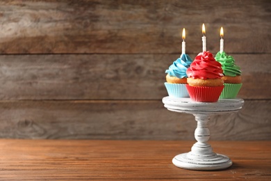 Photo of Delicious birthday cupcakes with candles on table