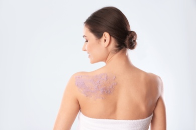 Photo of Young woman with body scrub on her back against white background