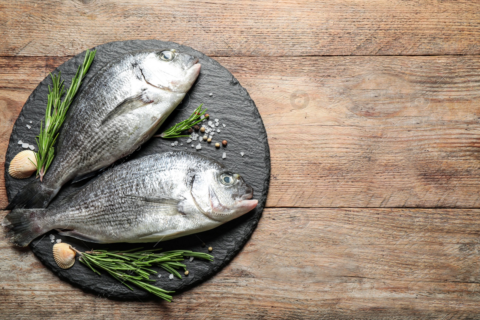 Photo of Raw dorada fish on wooden table, top view. Space for text