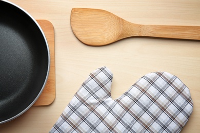 Flat lay composition with oven glove and frying pan on wooden table