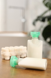 Mini bottles of cosmetic products and soap on wooden table against blurred background