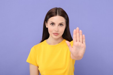 Photo of Woman showing stop gesture on violet background