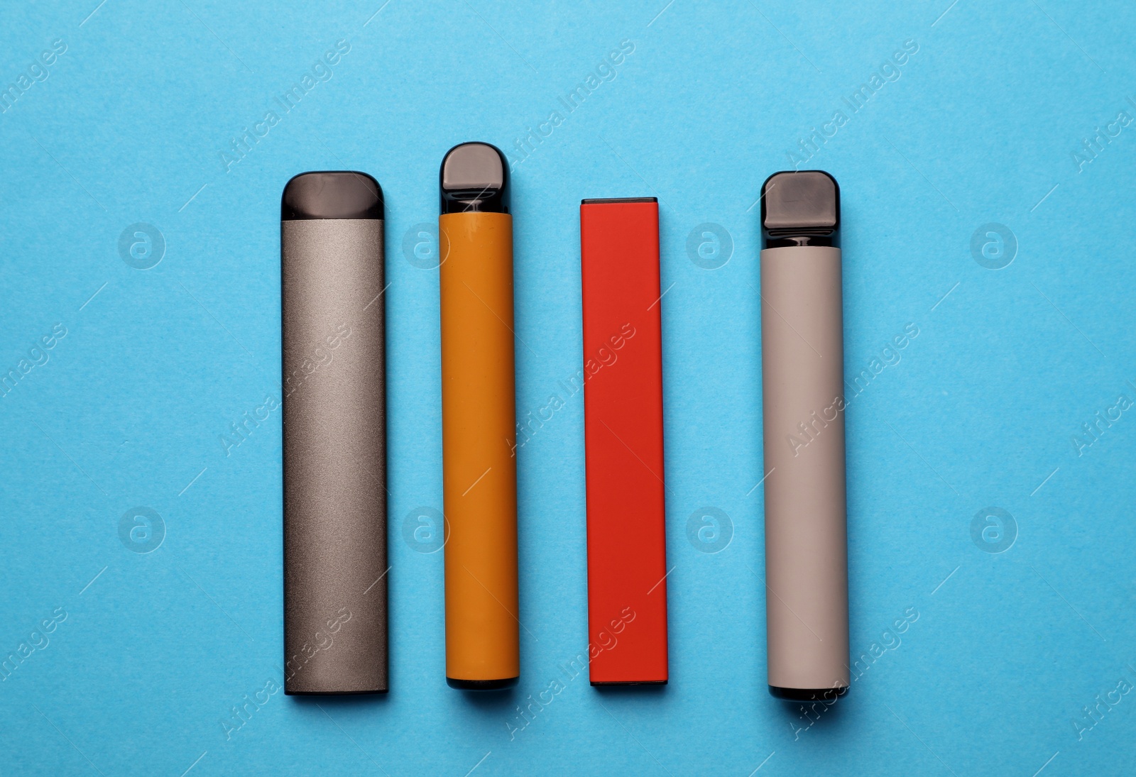 Photo of Different electronic cigarettes on light blue background, flat lay