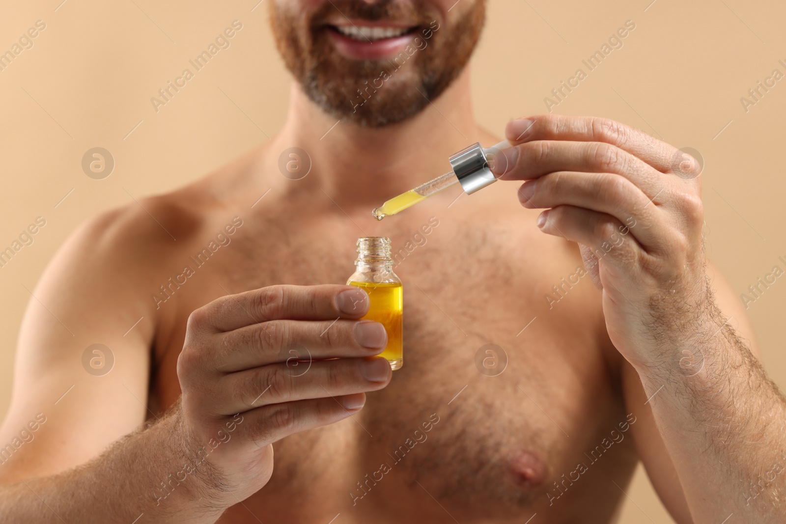 Photo of Smiling man with cosmetic serum on beige background, selective focus