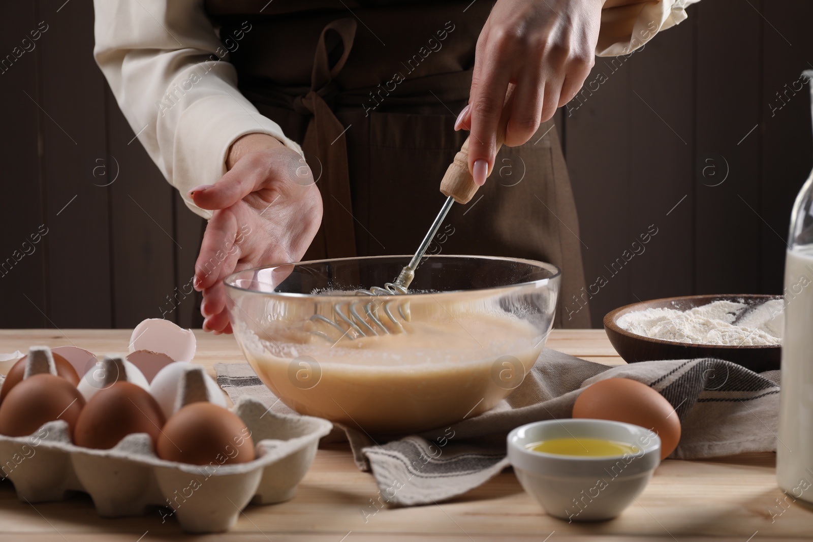 Photo of Woman making dough with whisk in bowl at table, closeup