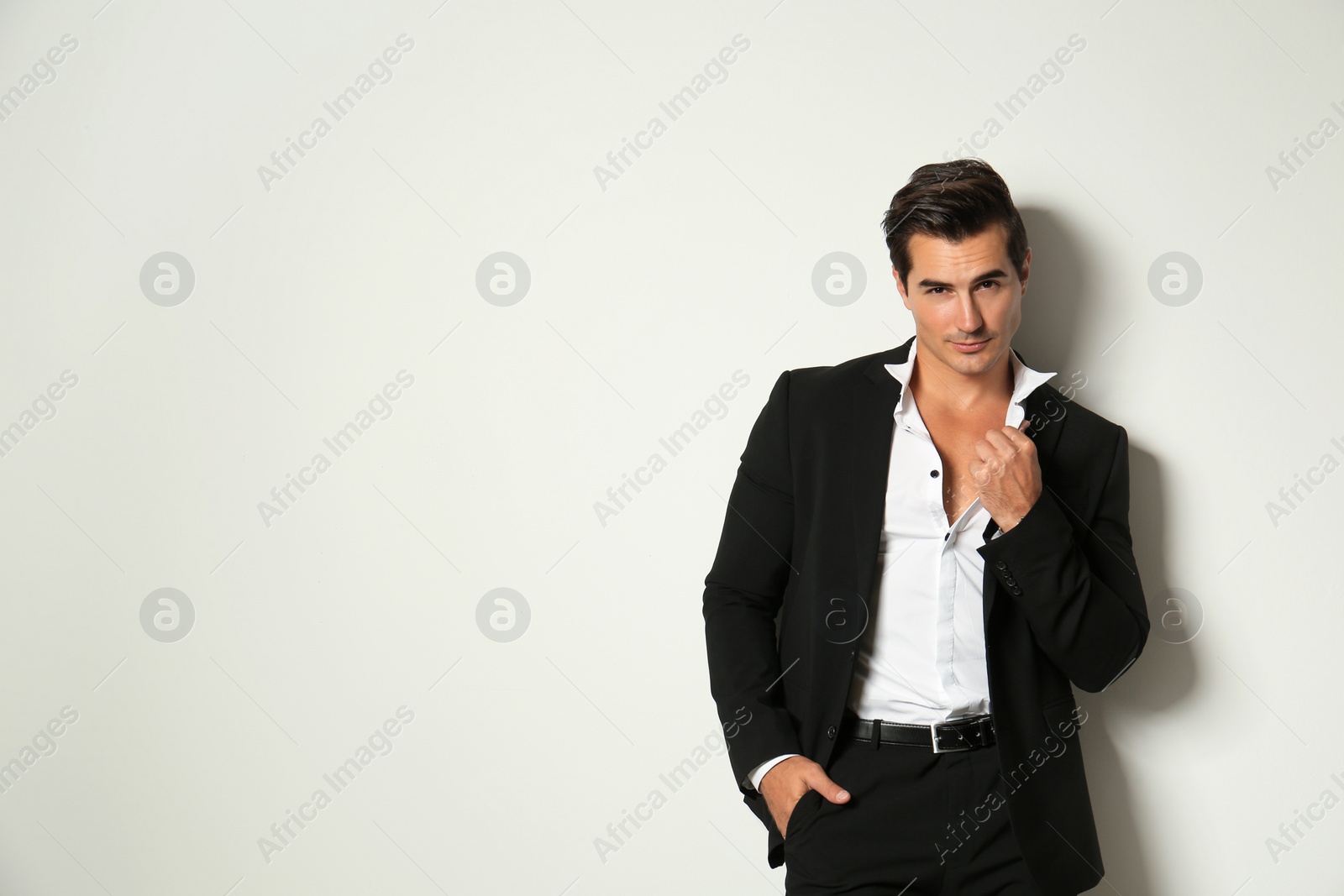 Photo of Handsome young man in elegant suit on light beige background. Space for text