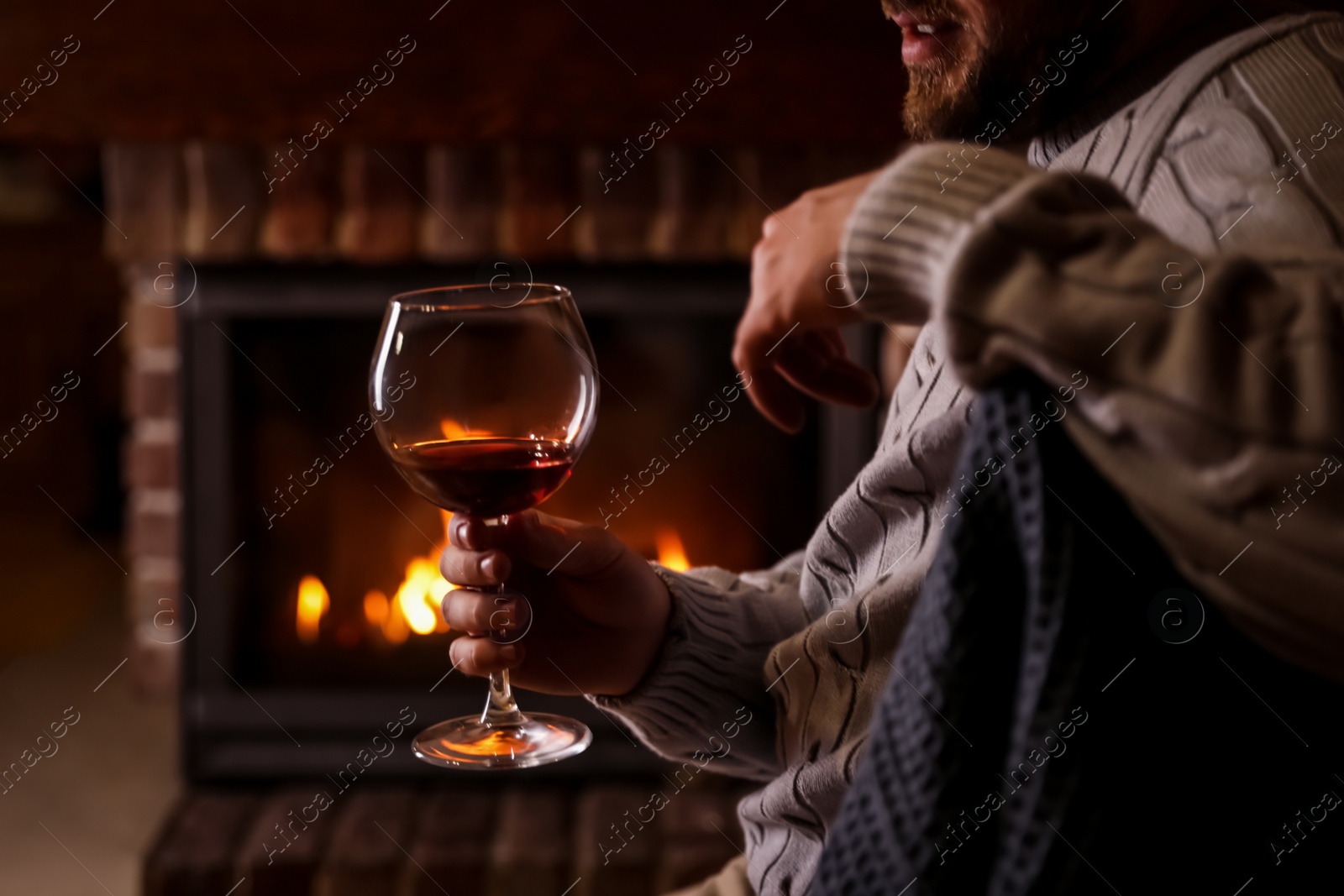 Photo of Man with glass of wine near fireplace at home, closeup