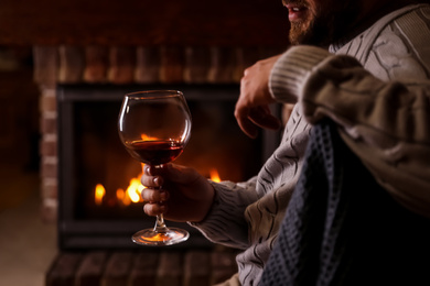 Photo of Man with glass of wine near fireplace at home, closeup