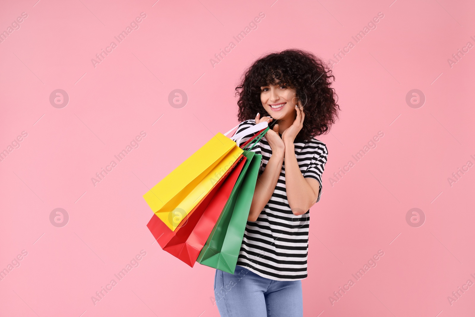 Photo of Happy young woman with shopping bags on pink background