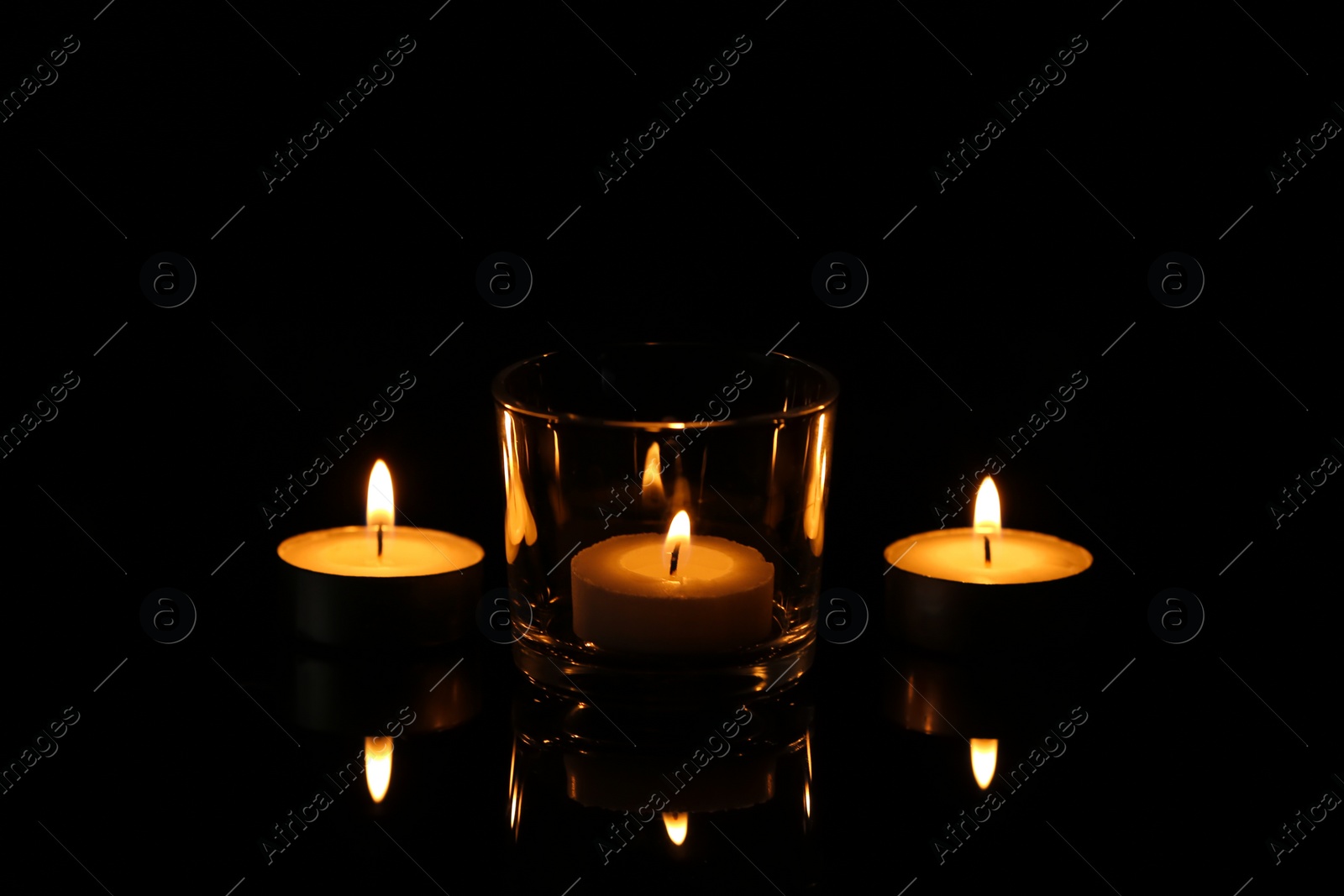Photo of Burning small wax candles in darkness. Funeral symbol