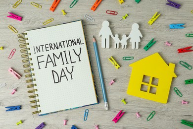 Photo of Happy Family Day. Flat lay composition with notebook, figures and stationery on wooden table