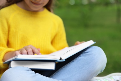 Image of Little girl reading book in park, closeup