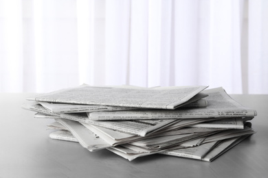 Pile of newspapers on grey table. Journalist's work