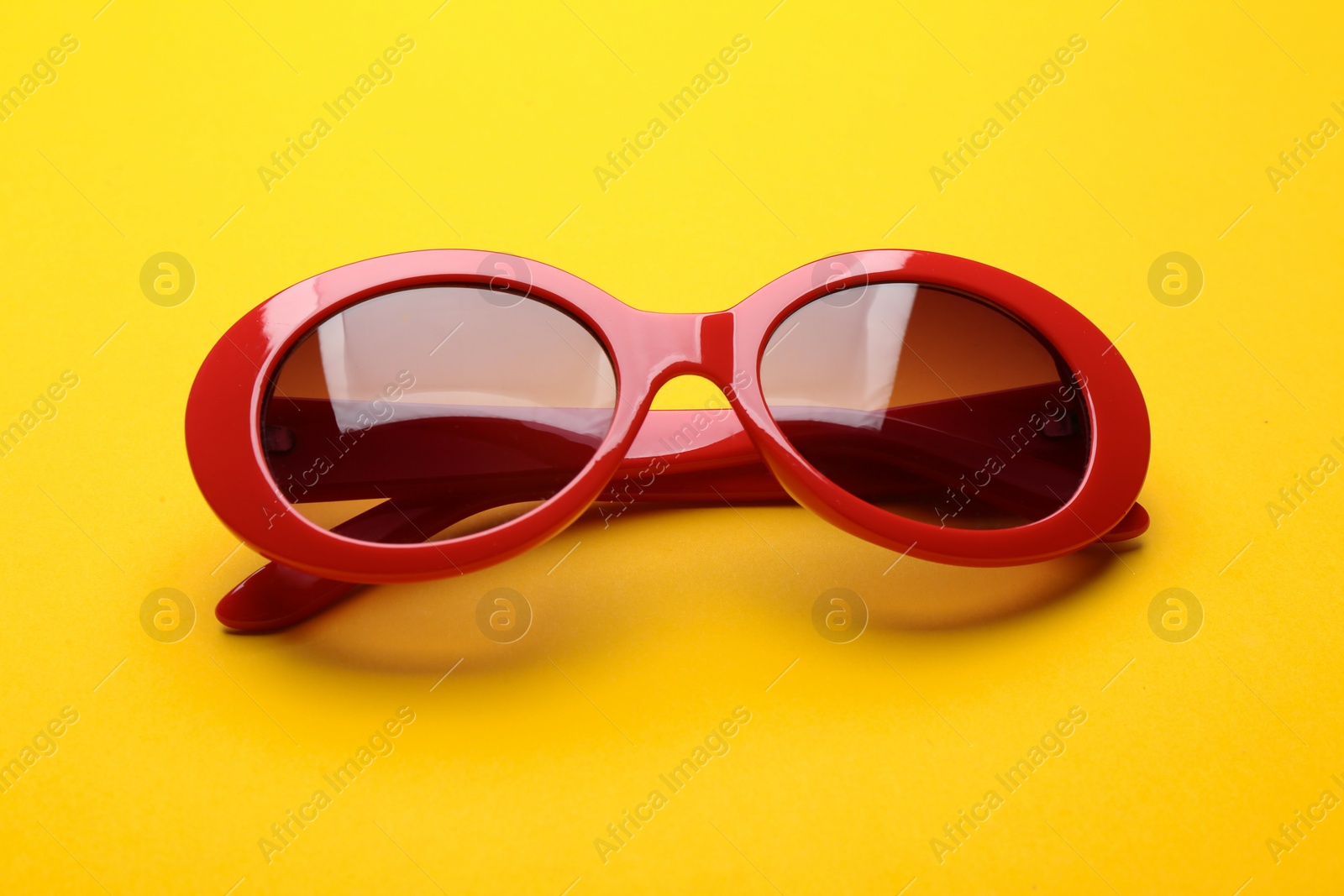 Photo of Stylish sunglasses on yellow background. Fashionable accessory