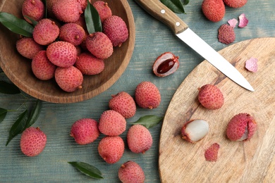 Photo of Fresh ripe lychee fruits and knife on wooden table, flat lay
