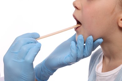 Photo of Doctor examining girl`s oral cavity with tongue depressor on white background, closeup