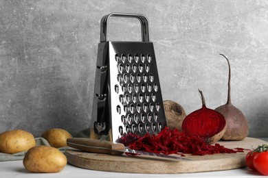 Photo of Grater and fresh ripe vegetables on table