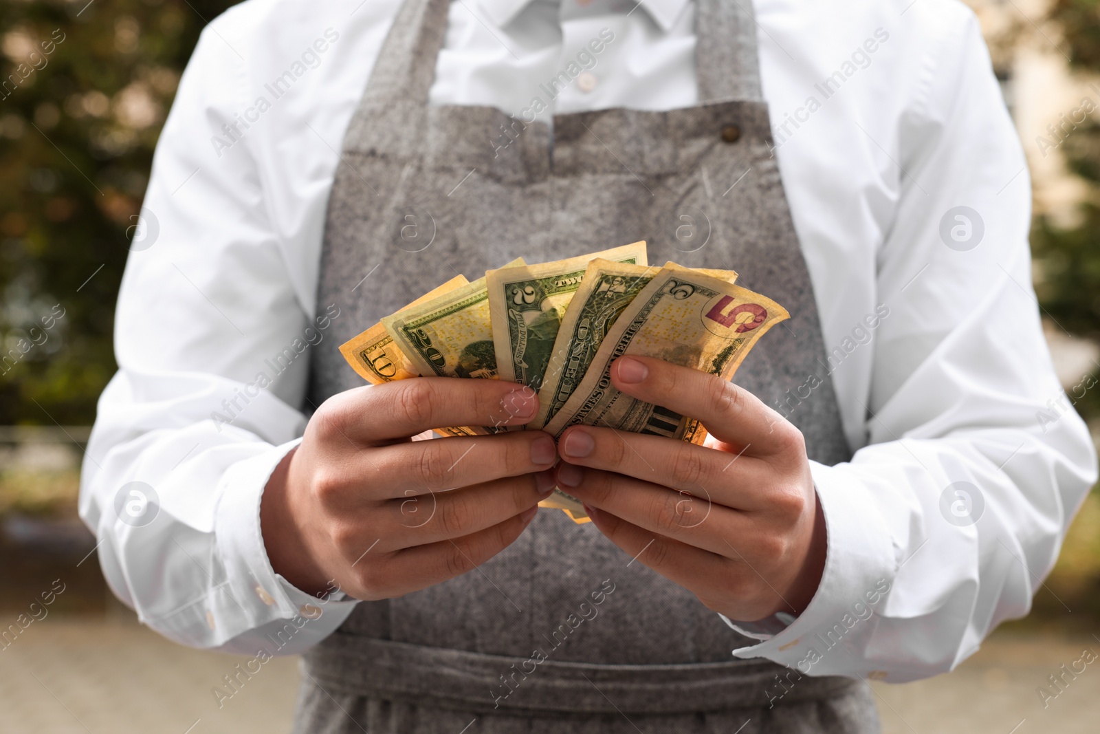 Photo of Waiter holding tips in outdoor cafe, closeup