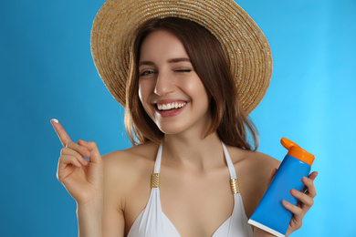 Photo of Young woman with sun protection cream on light blue background