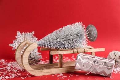 Photo of Beautiful Christmas composition with miniature sleigh on red background